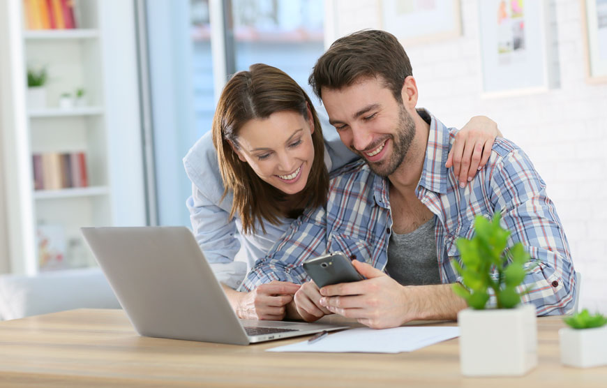 Couple at table with laptop, smartphone and paperwork